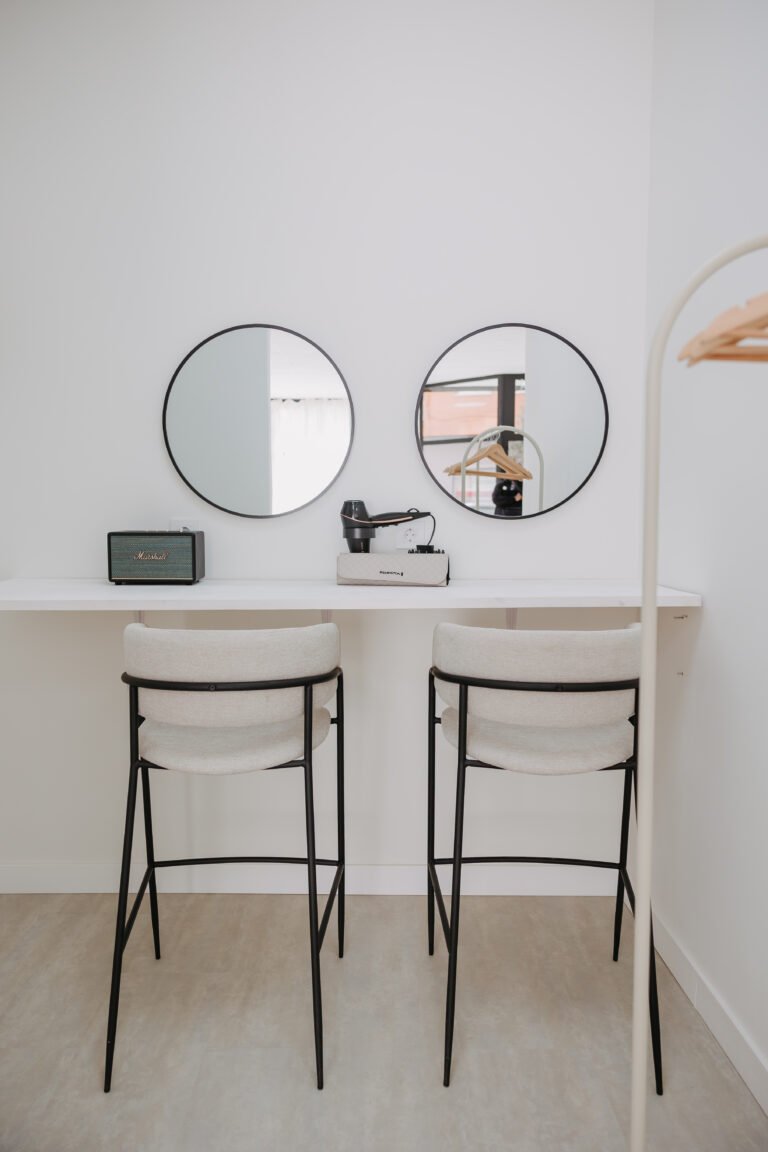 Zona de maquillaje con dos espejos redondos y taburetes