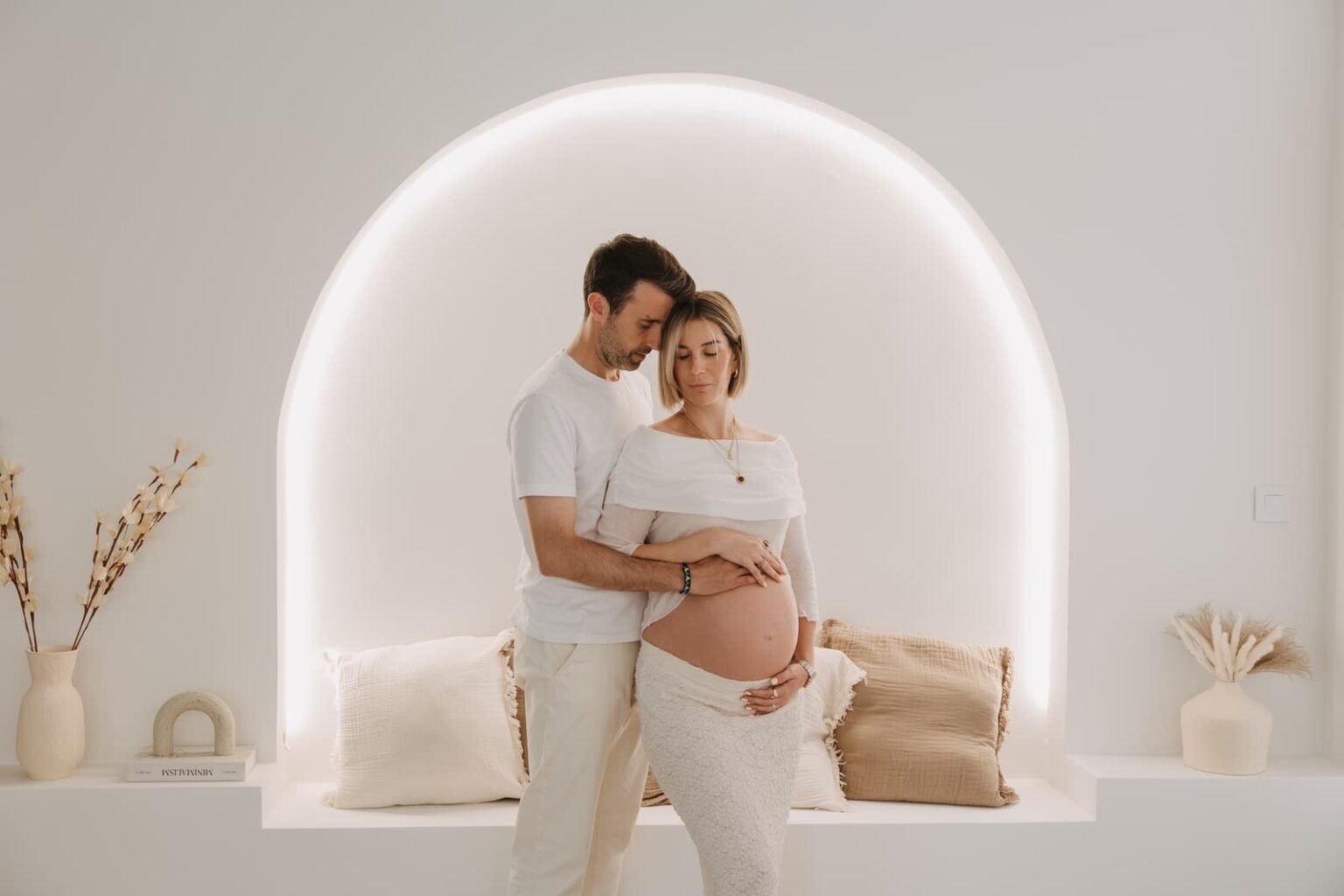Sesión de embarazo de una pareja bajo el arco iluminado