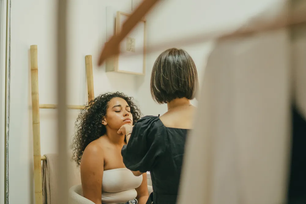 Maquilladora preparando a una modelo frente al espejo