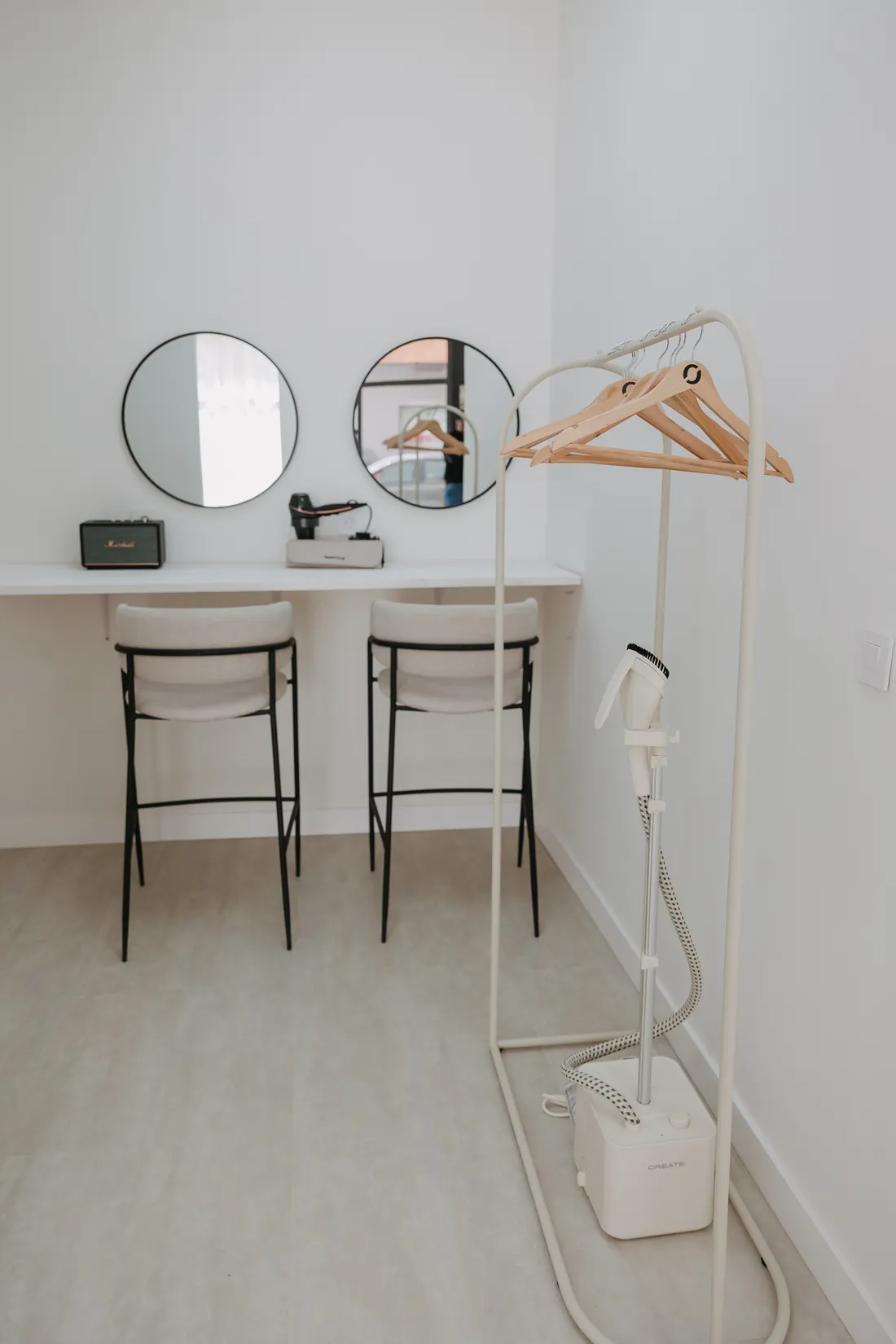 Zona de maquillaje con espejos redondos y burro de ropa