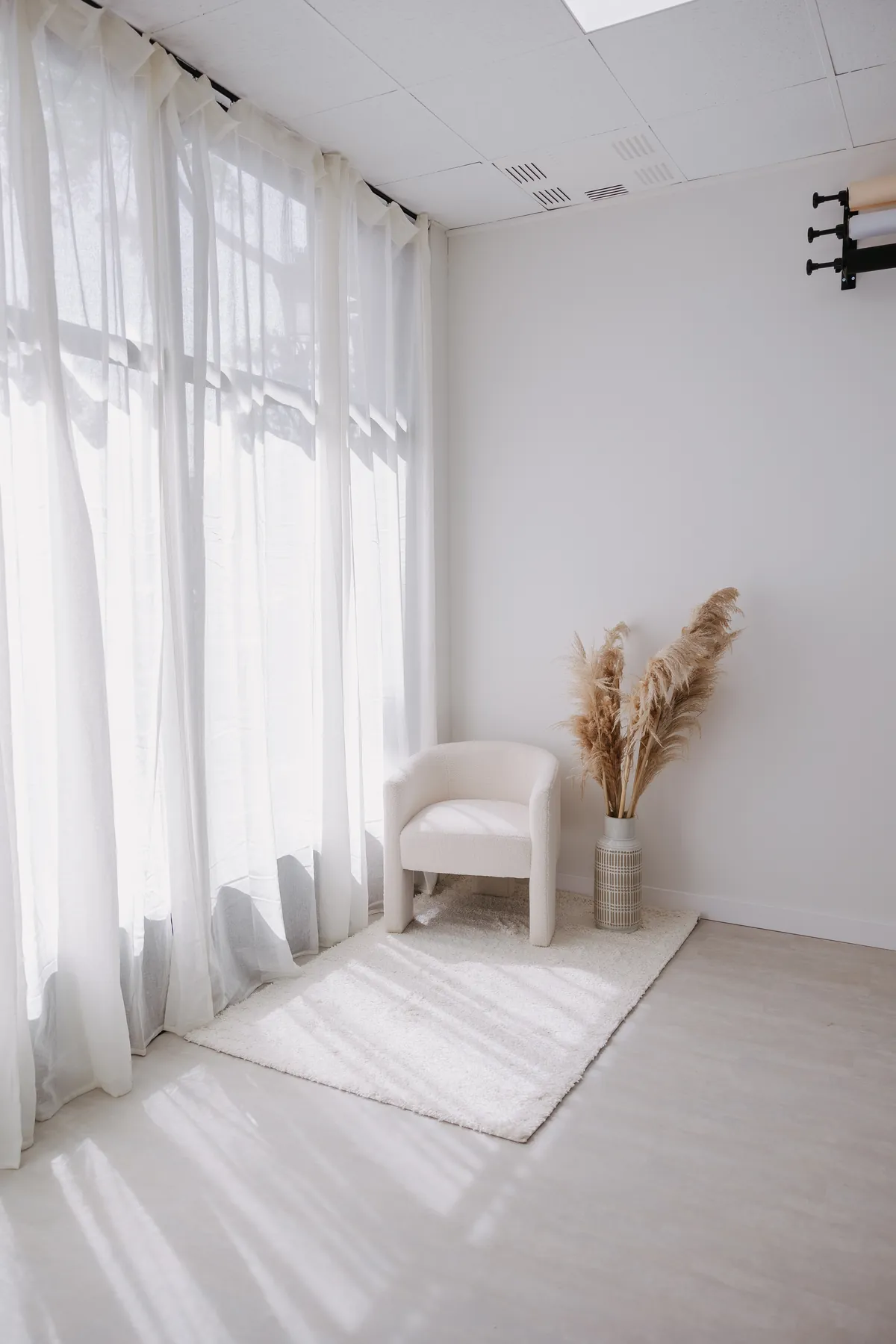 Rincón del estudio con sillón, cortinas y luz natural