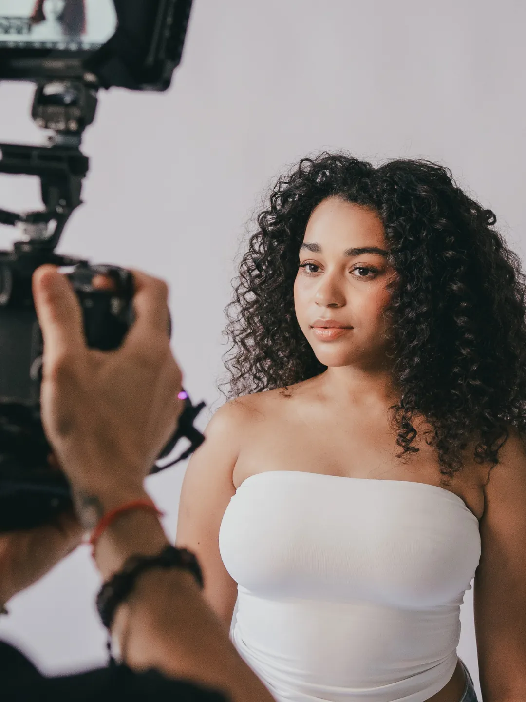 Un videógrafo graba a una modelo frente a un fondo claro durante una producción en Claro Content Studio