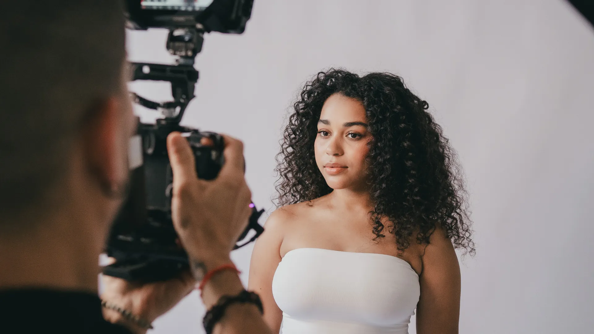 Un videógrafo graba a una modelo frente a un fondo claro durante una producción en Claro Content Studio
